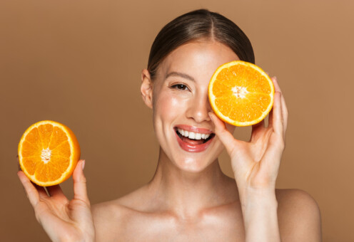 Image closeup of healthy half-naked woman smiling and holding two orange parts Kad je vrijeme za pregled dermatologa?